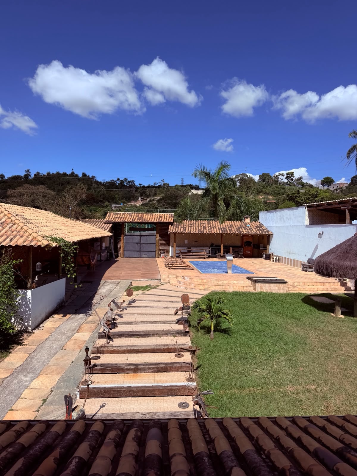 Vista geral do espaço com piscina, gramado e caminho de pedras