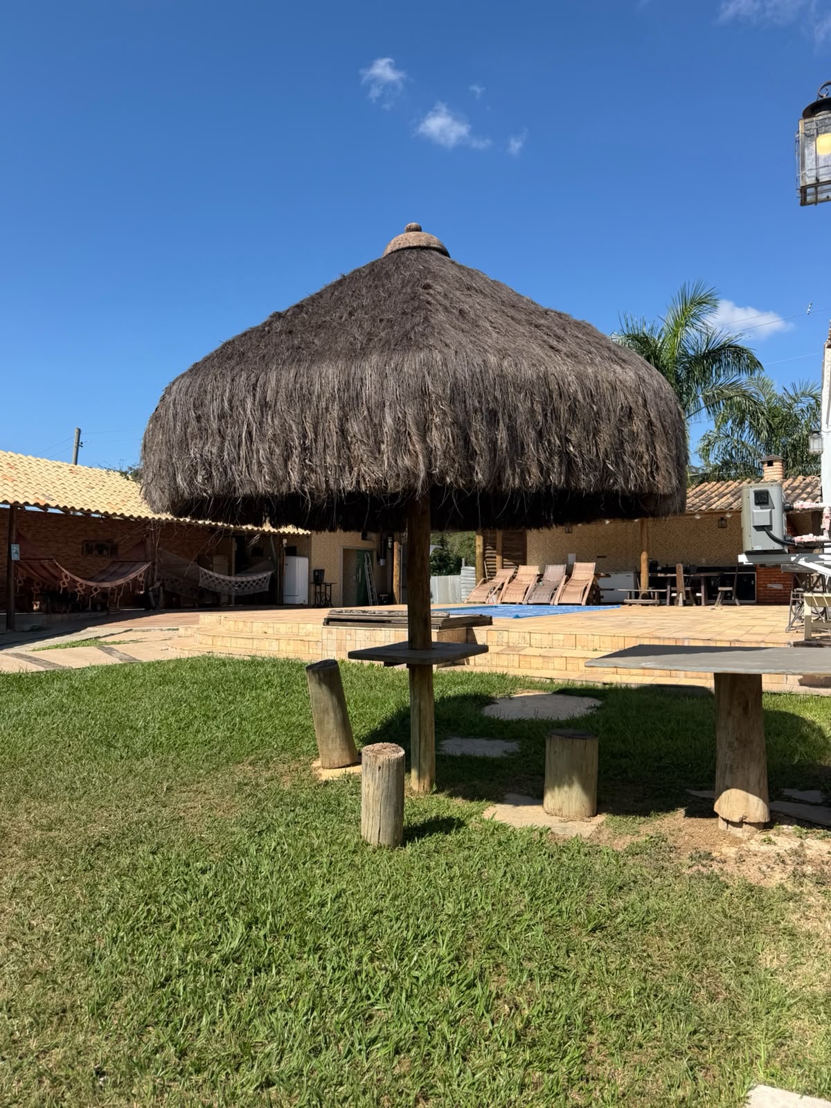 Gramado com quiosque de palha e mesas